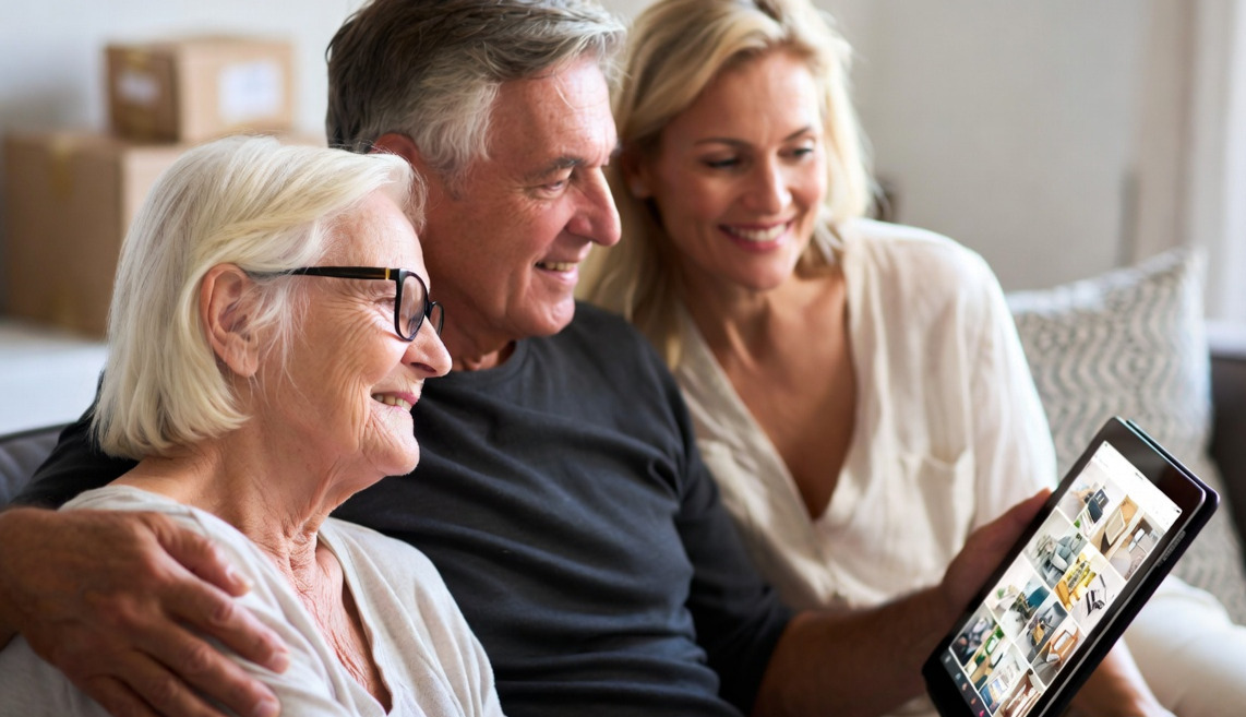 An elderly mother with her children reviewing her belongings on an Ipad